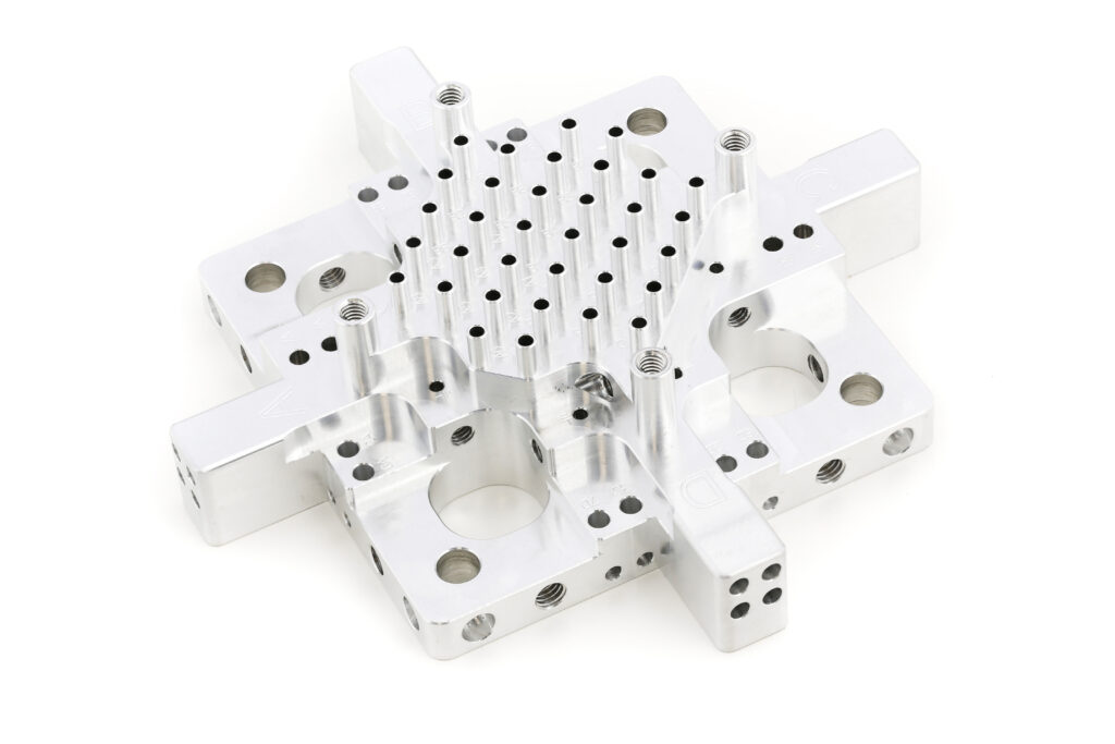 Präzise CNC-gefrästes Aluminiumbauteil mit zahlreichen Bohrungen, Gewinden und Aussparungen für komplexe Fertigung bei HFH Präzisionsmechanik.