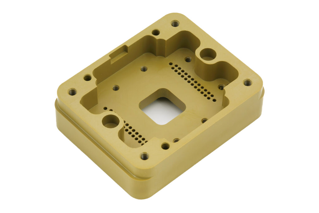 Ein goldfarbenes CNC-gefrästes Aluminiumbauteil mit präzisen Bohrungen, Gewinden und Aussparungen aus der Fertigung in Bayern.